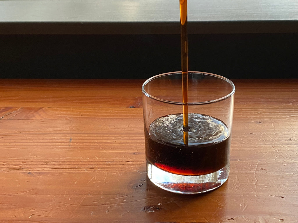 Thick rich dark organic Passamaquoddy maple syrup being poured into a glass 