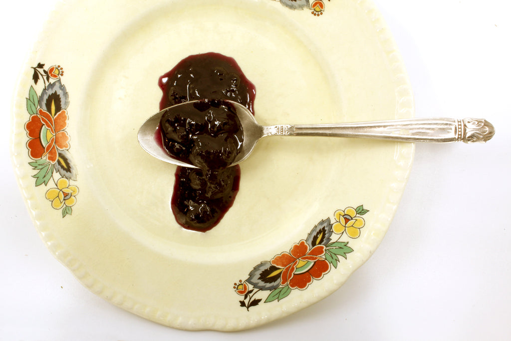 Desert Blueberry Gin Jam displayed on spoon, thick rich texture with visible mini wild blueberries and specks of sage, juniper 